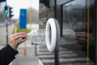 Műanyag palack behelyezése kültéri visszaváltó automatába.