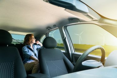 Autó utasteréből látható kilátás az útra, a háttérben modern energetikai infrastruktúrával.