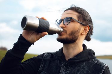 Fémkulacsból ivó férfi