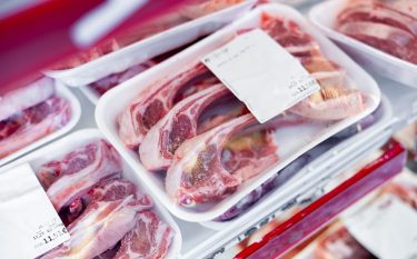 Fóliázott húsok láthatók tálcás csomagolásban egy hűtőpultban.