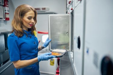 Egy dolgozó csomagolt ételt kezel, amelynél a hőmérsékletre reagáló címke segíti az állapot ellenőrzését.