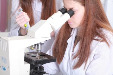 Kutató mikroszkóp alatt vizsgál biopolimer alapú mintát laboratóriumi környezetben.