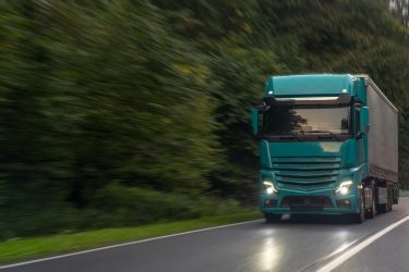 Egy nyerges vontató halad országúton nyári körülmények között.